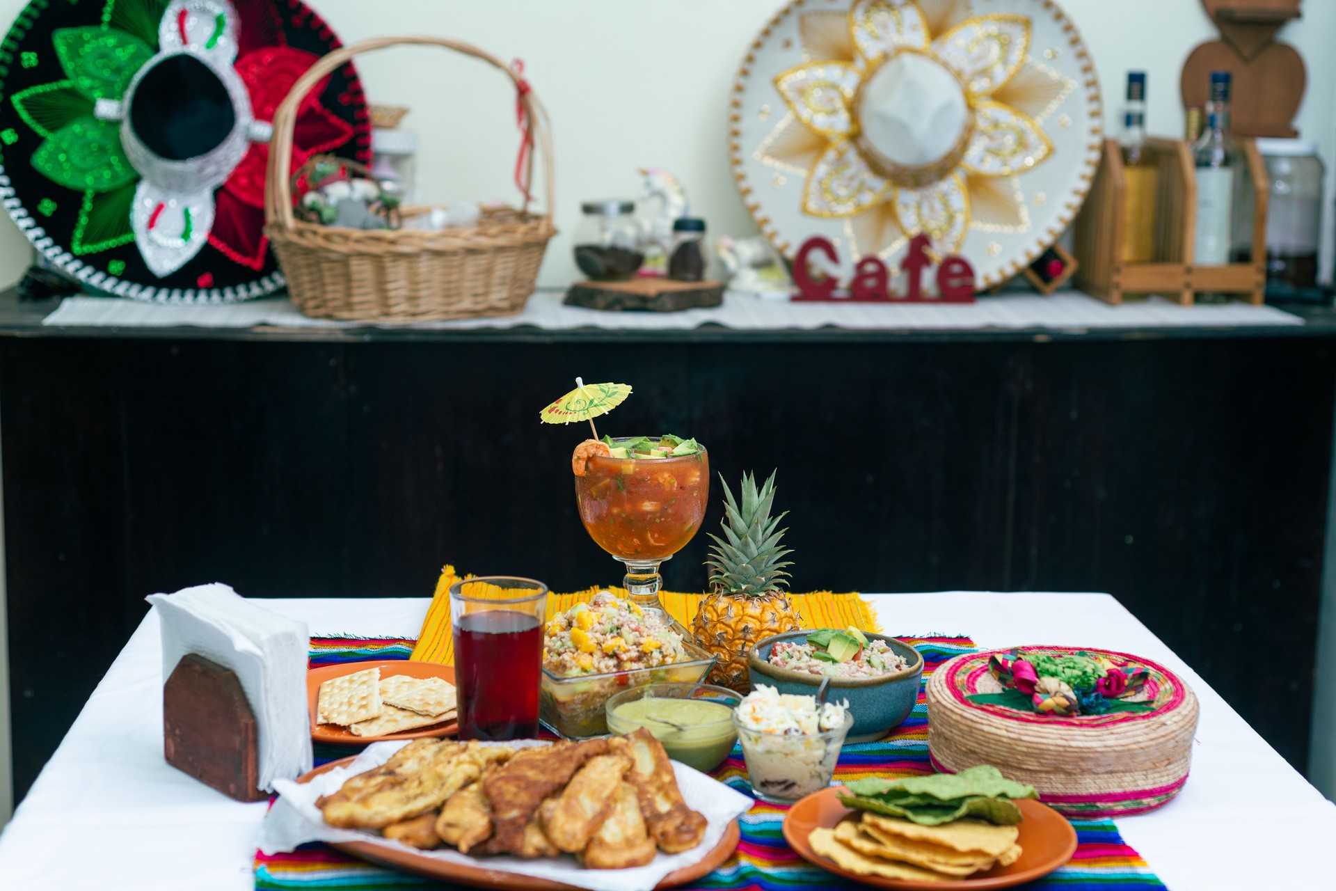 A table full of delicious Mexican dishes, such as shrimp cocktail, various sauces, fried fish, ceviche and tortillas